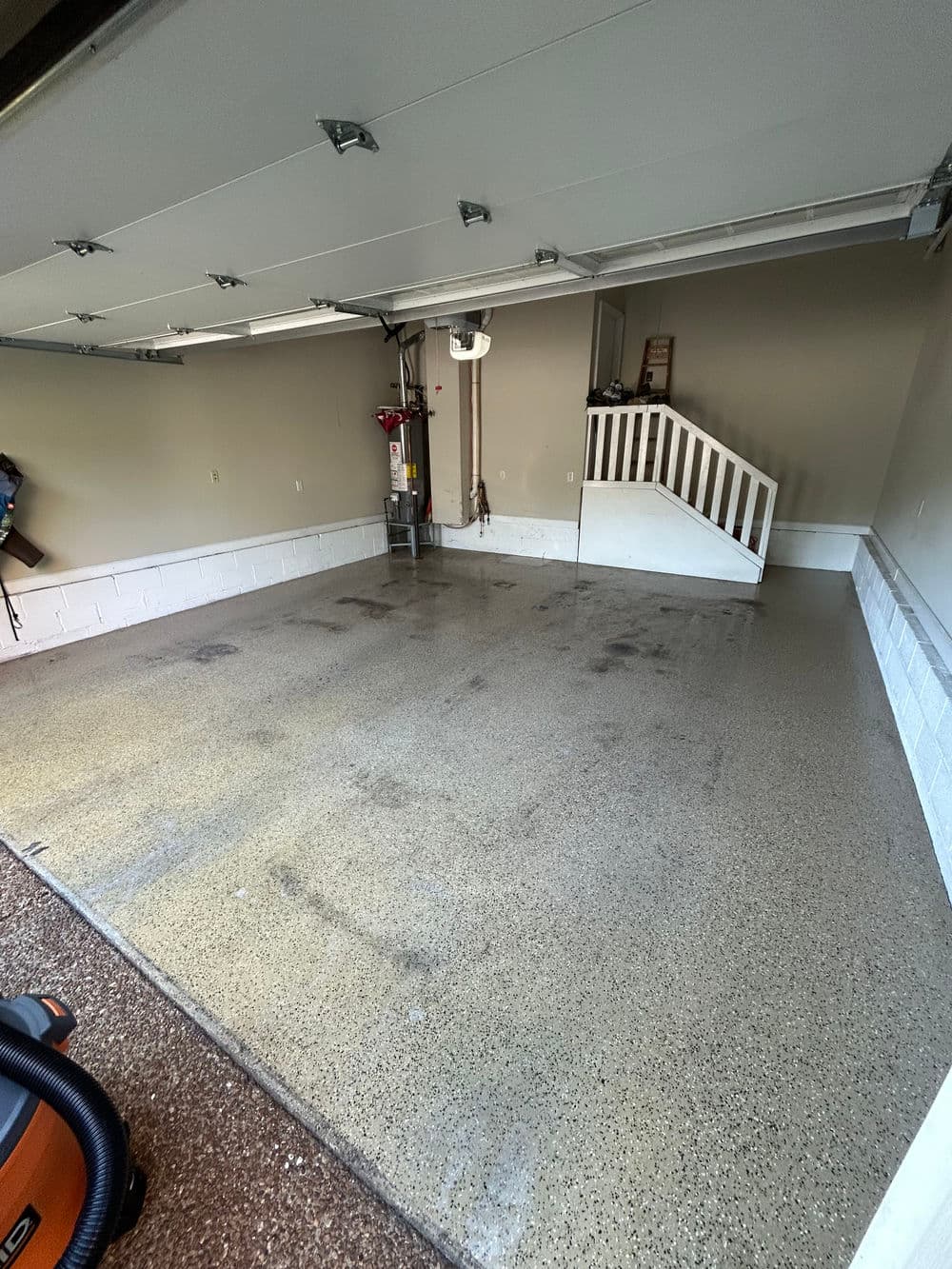 Clean garage interior with modern flooring and stairs leading to an upper level.
