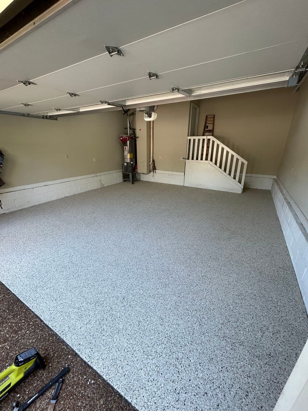 Clean, spacious garage with gray epoxy floor and white stairs, ideal for organization and storage.
